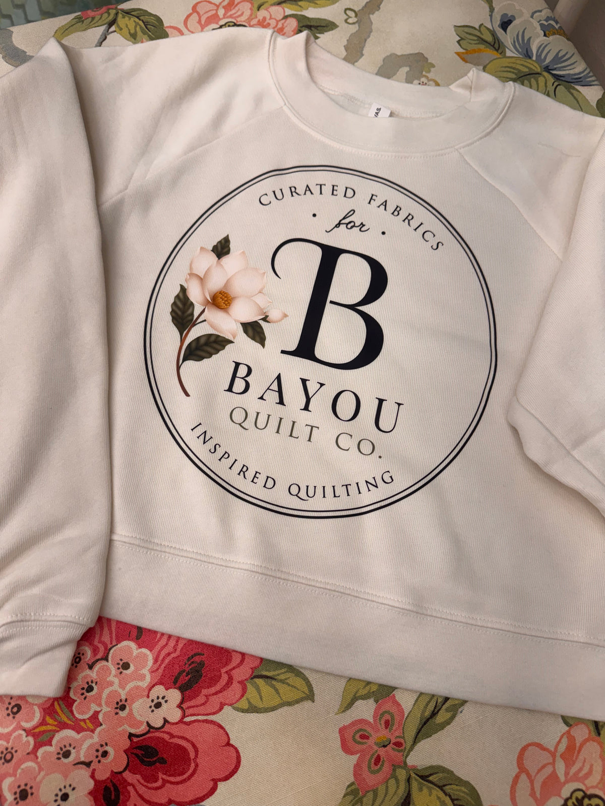 Bayou Quilt Co. women's raglan pullover fleece in Vintage White with round seal logo